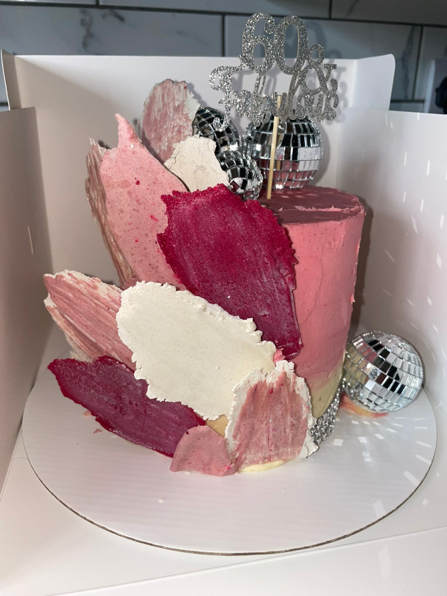 Pink ombre 60th birthday cake with buttercream shards and mirror ball decorations